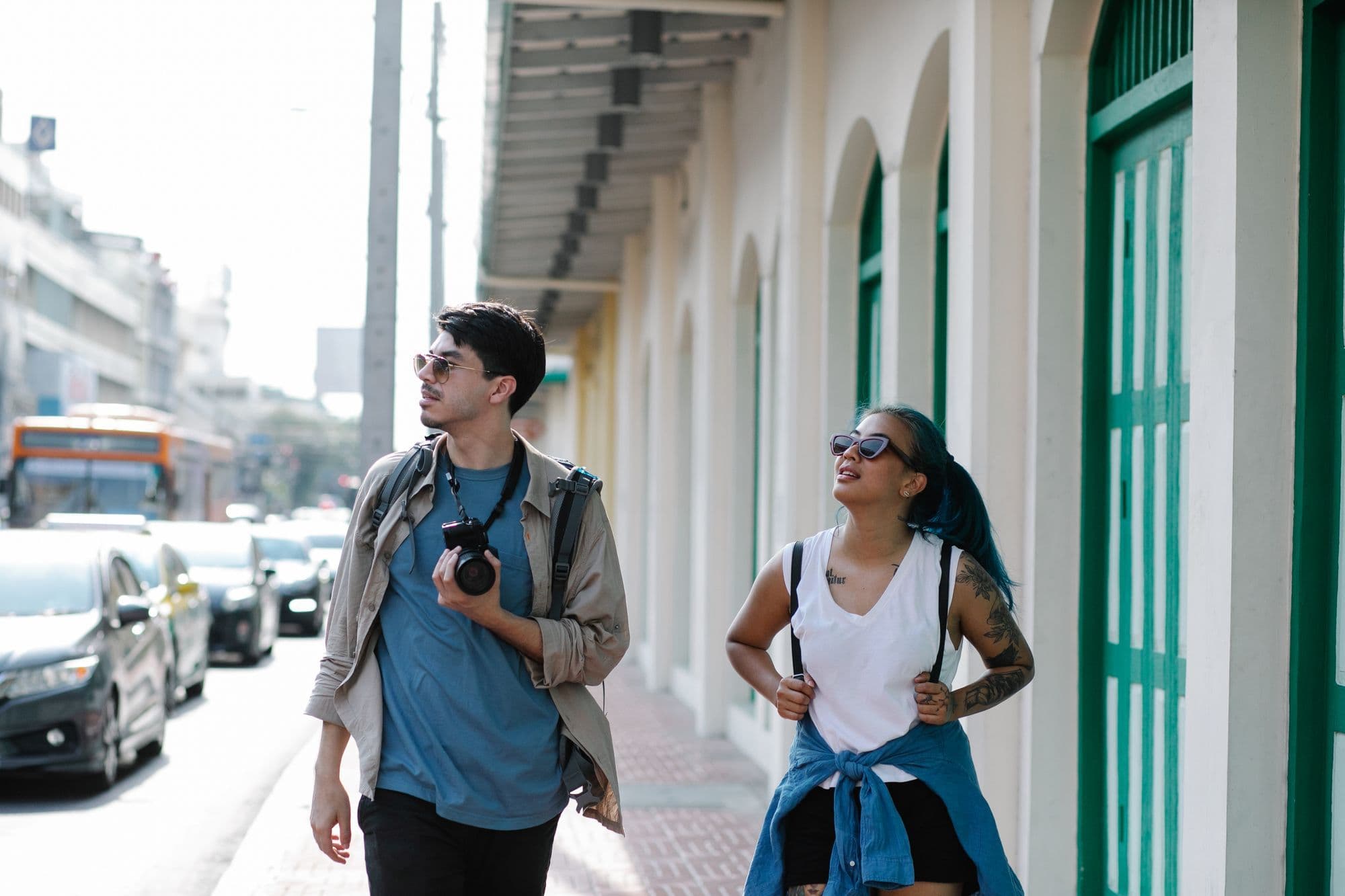 Two travelers walking together along a busy city street in daylight.