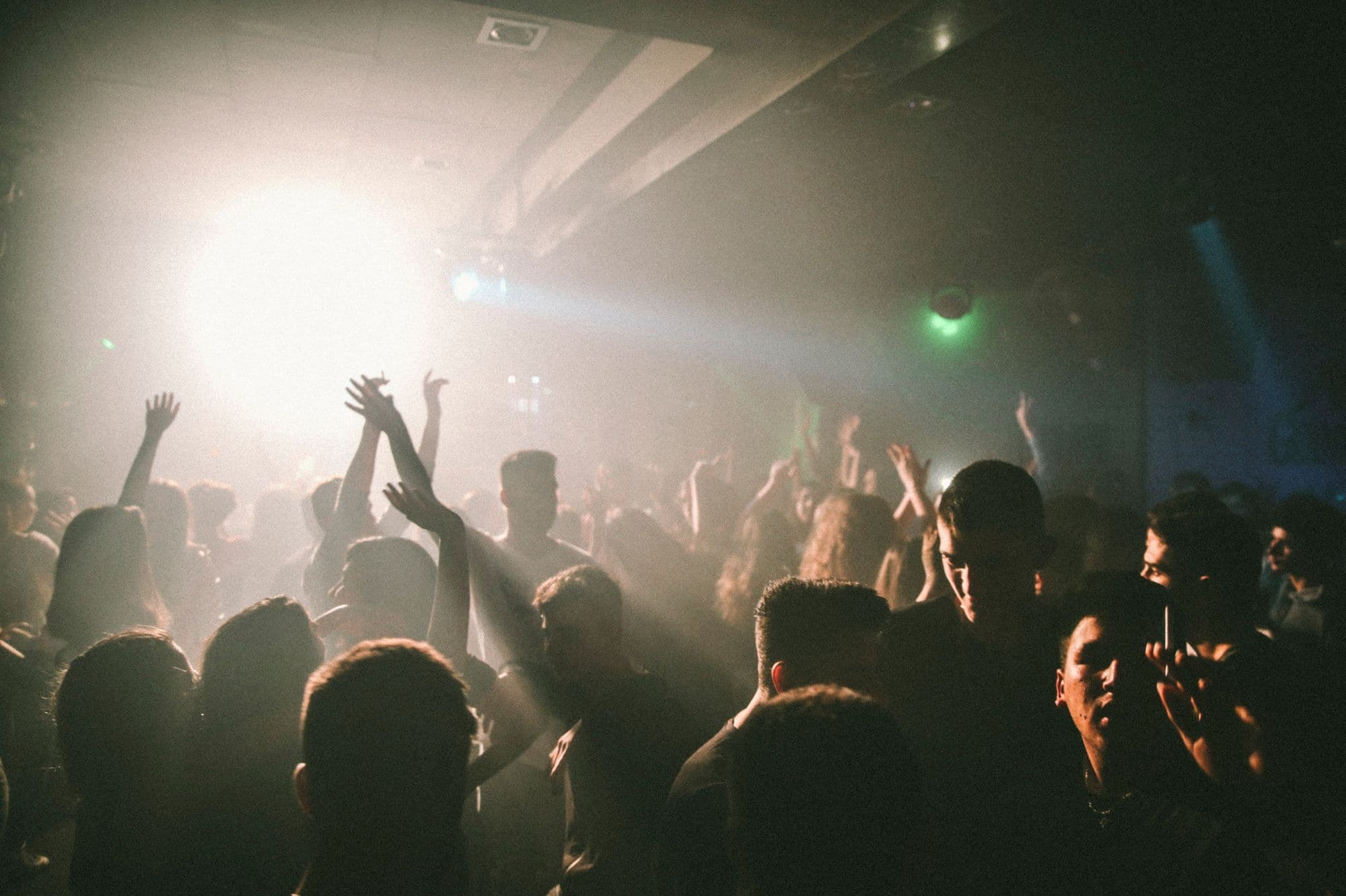 A crowded dance floor moves beneath blue and violet nightclub lights.