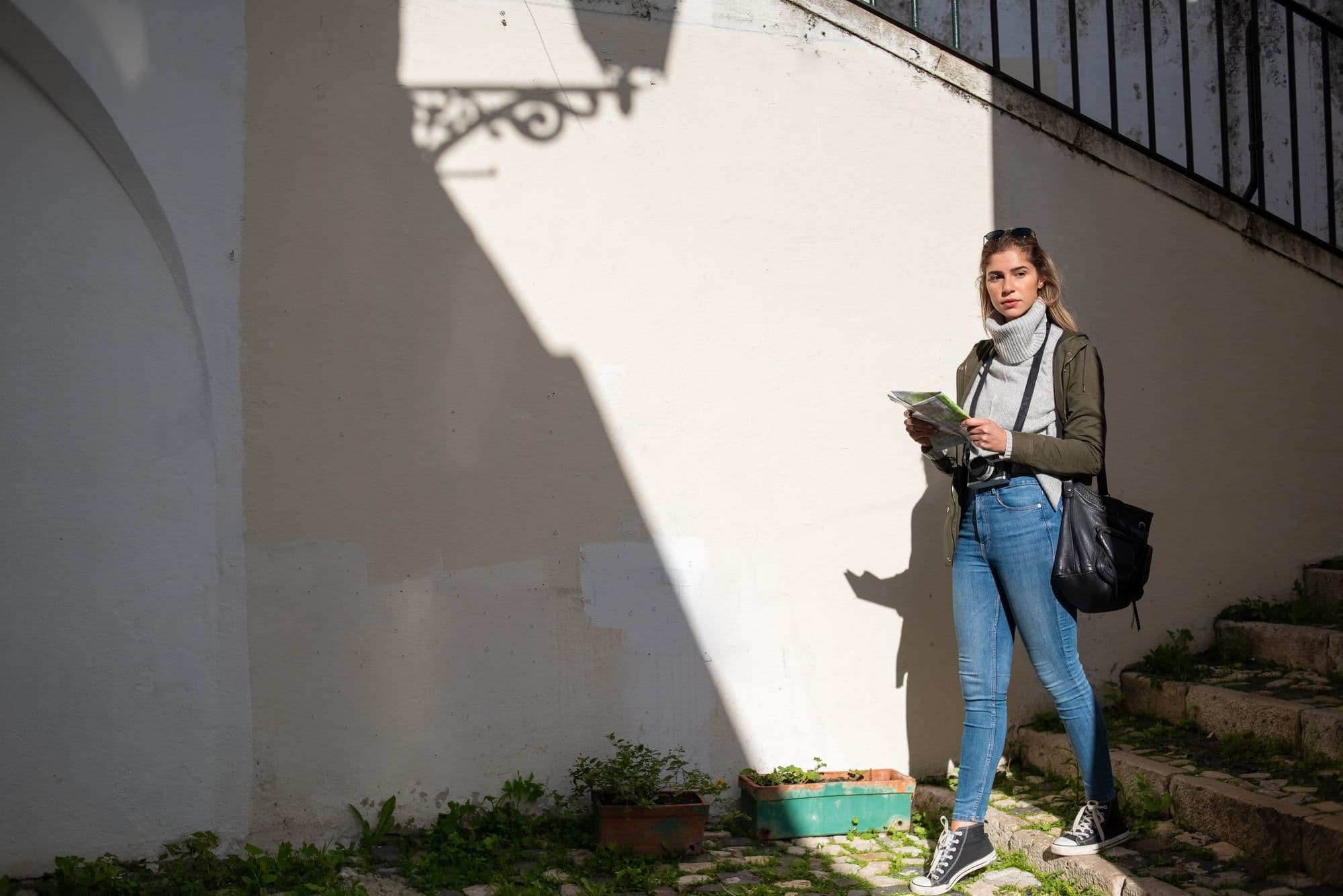 A traveler holds a map while standing on a city street.