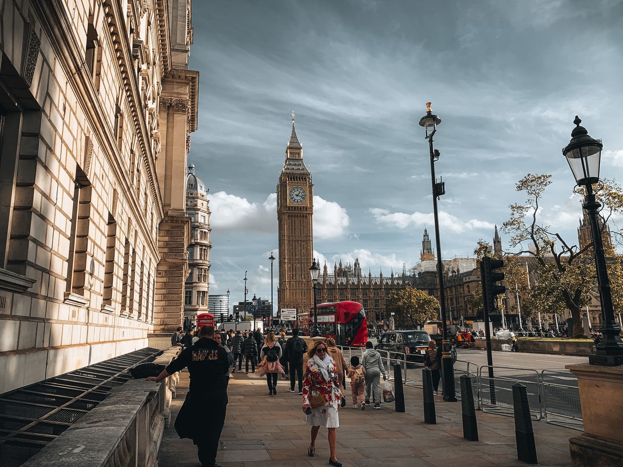 Big Ben rising above pedestrians and traffic on a clear London day.