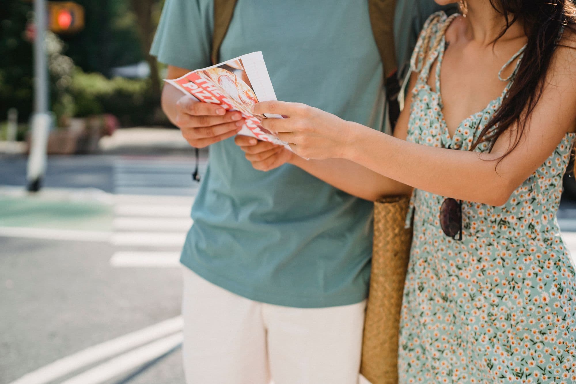 A couple using a folded paper map together beside a stone wall in a city.
