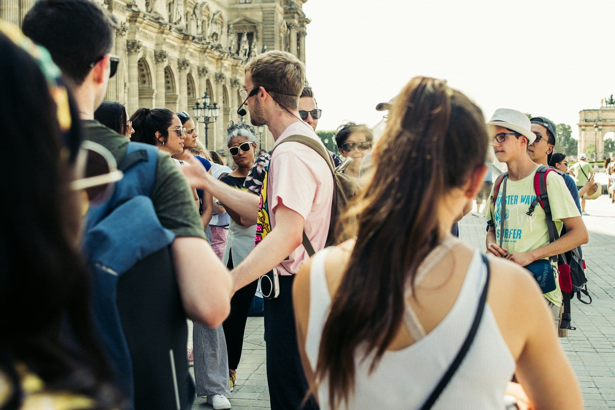 A group of people walk together along a sunny city street.