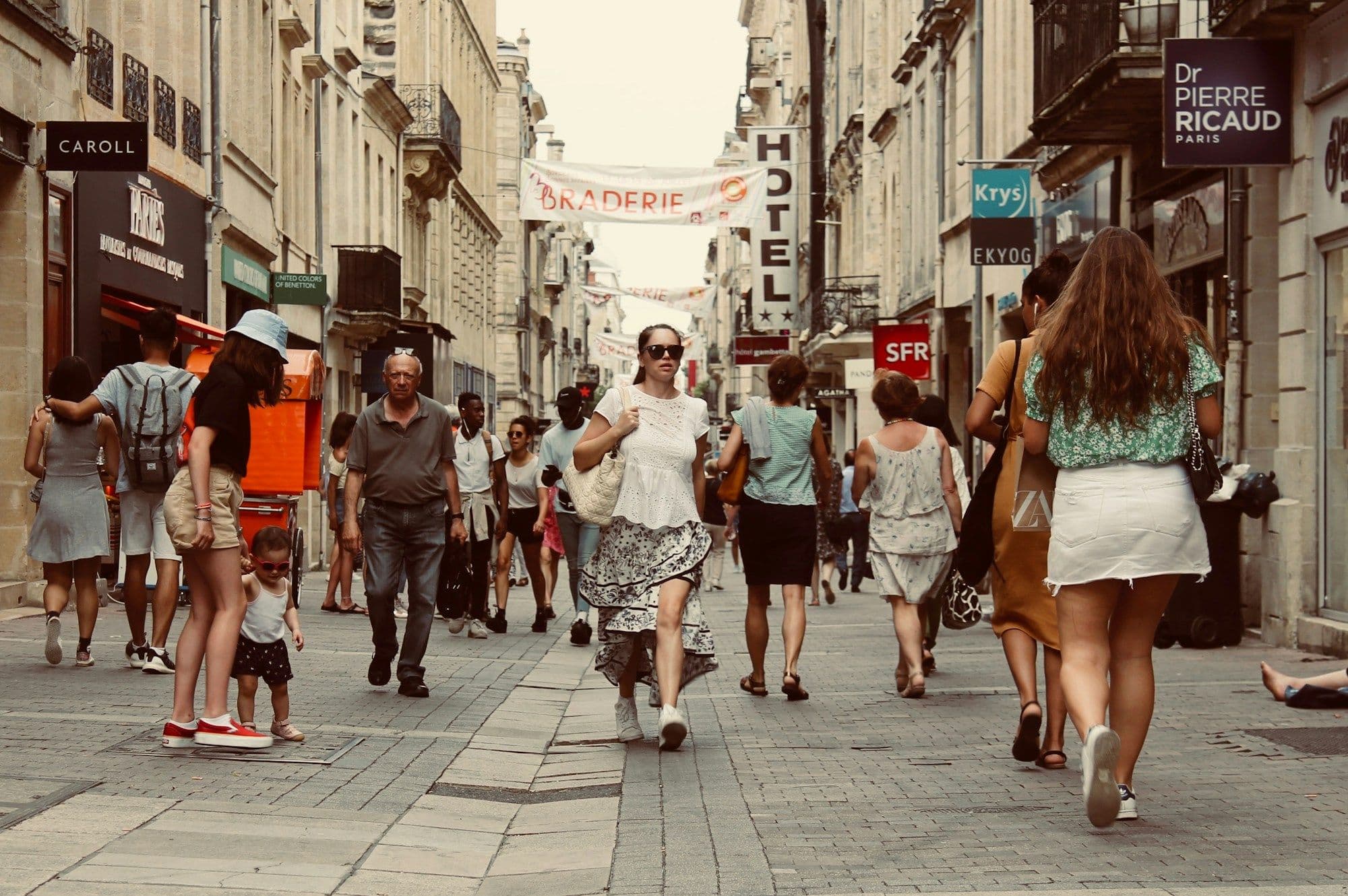 Pedestrians walking through a busy city street in daylight.
