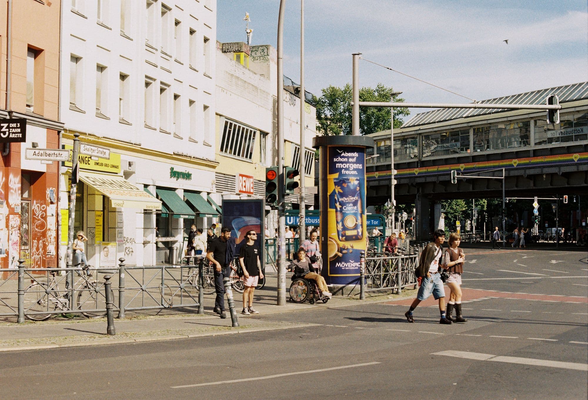 Pedestrians crossing a broad street between apartment blocks in Berlin's Kreuzberg district.