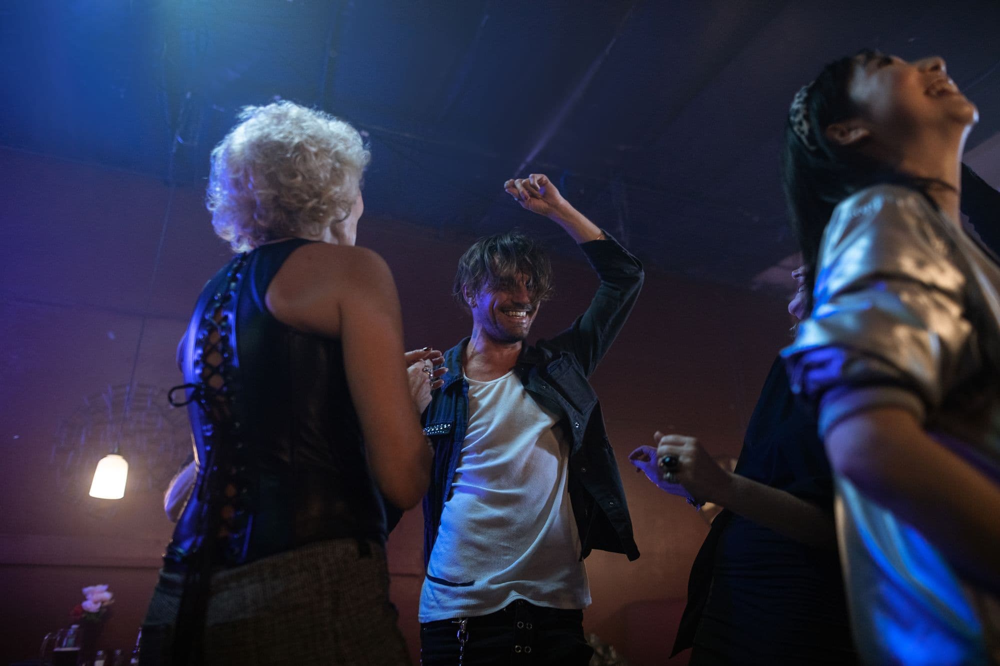 Friends dance together under coloured lights at an indoor party.