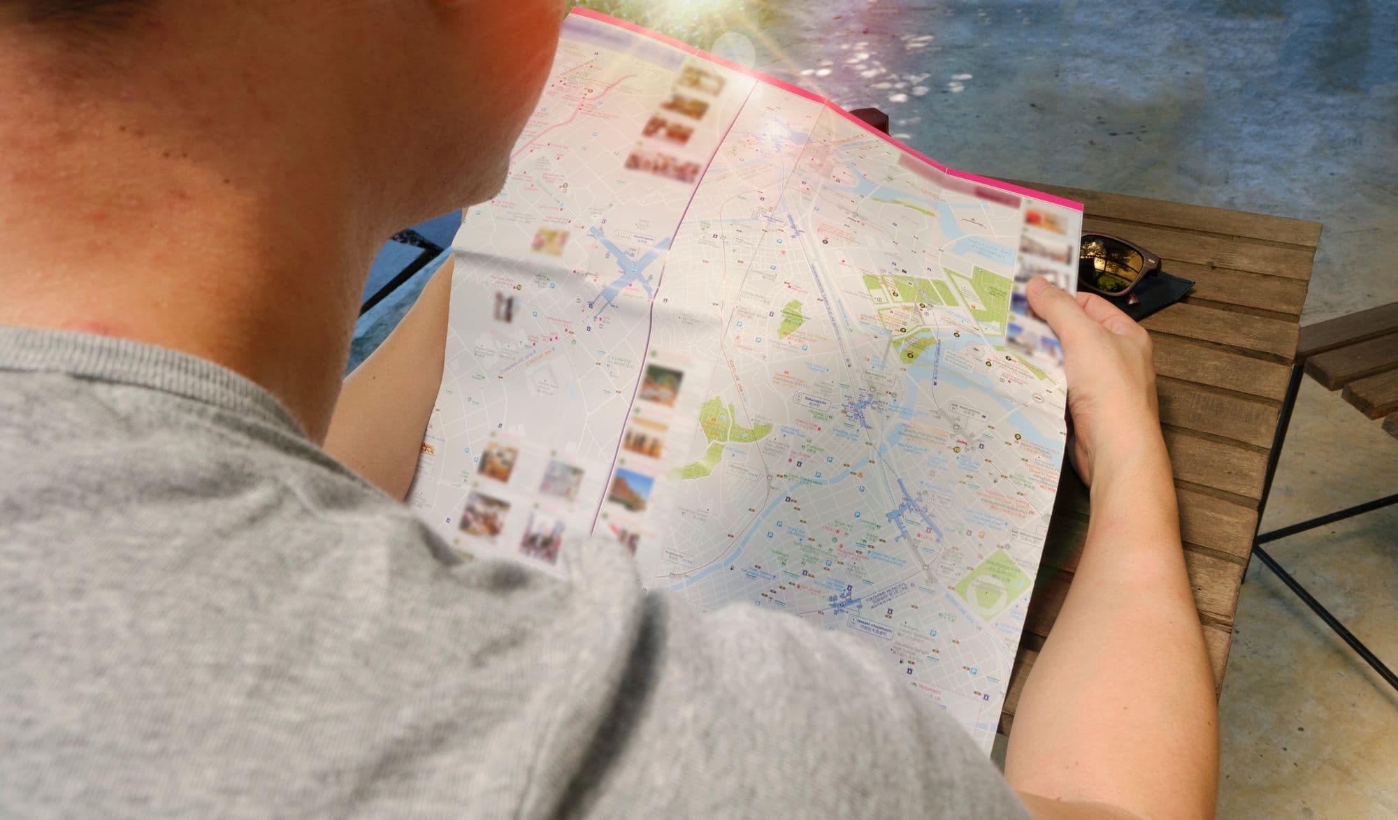 A traveler studies a folded paper map outdoors before setting off.