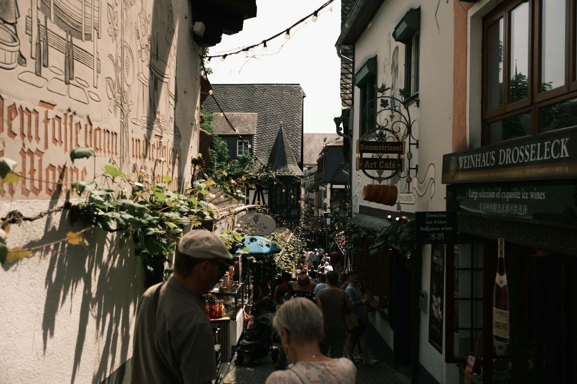 People walking down a narrow historic street lined with old European buildings.