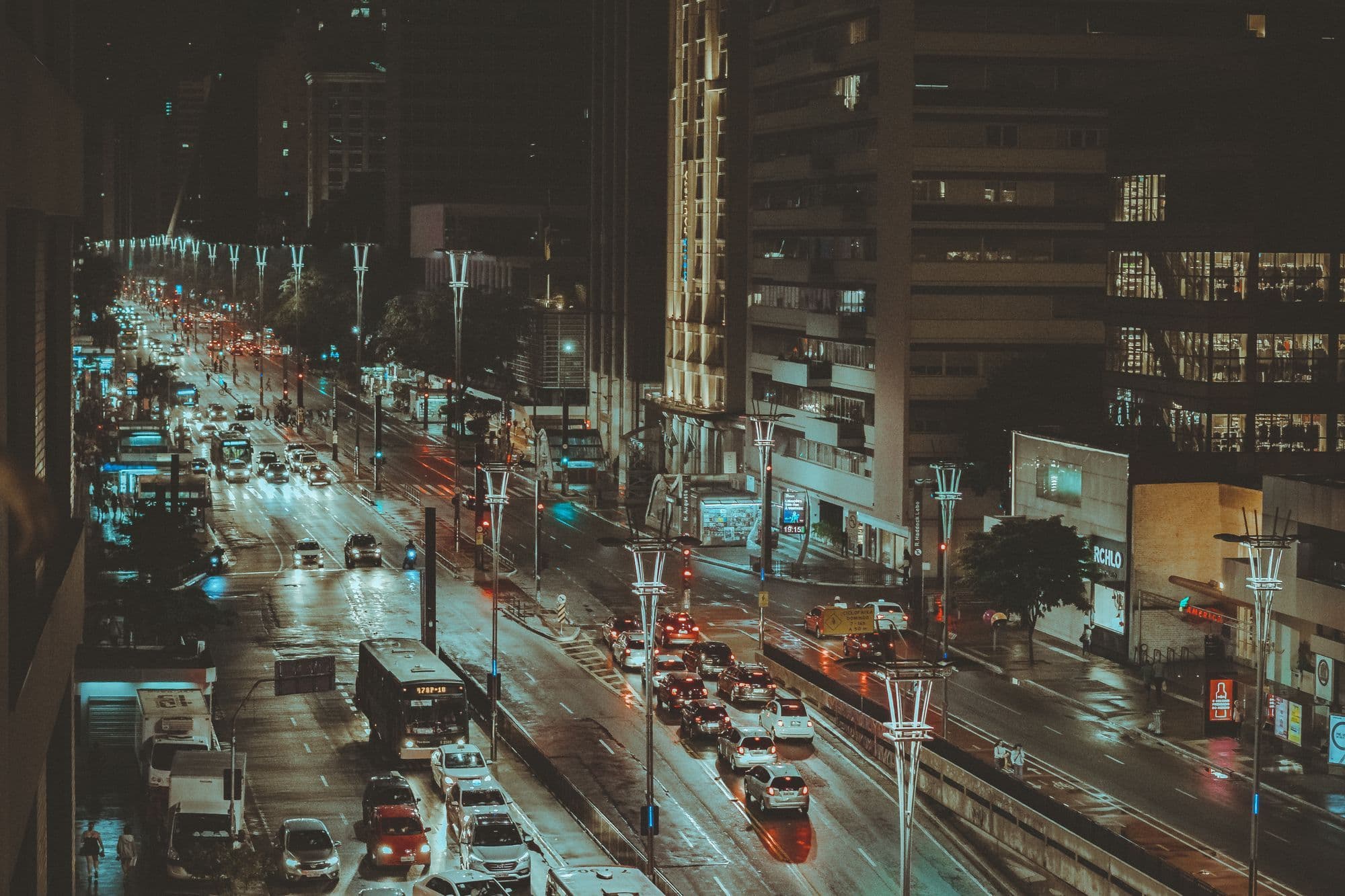 Headlights and red taillights streaming along a busy Bela Vista street at night.