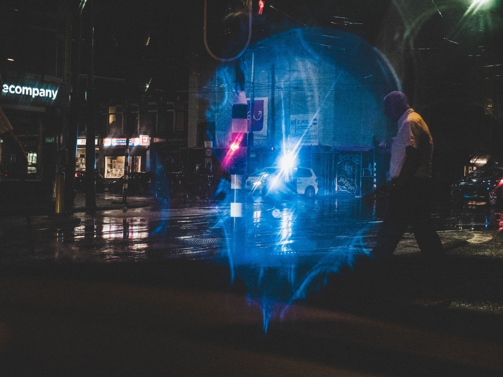 Wet Amsterdam pavement reflects streetlights as a person walks at night.