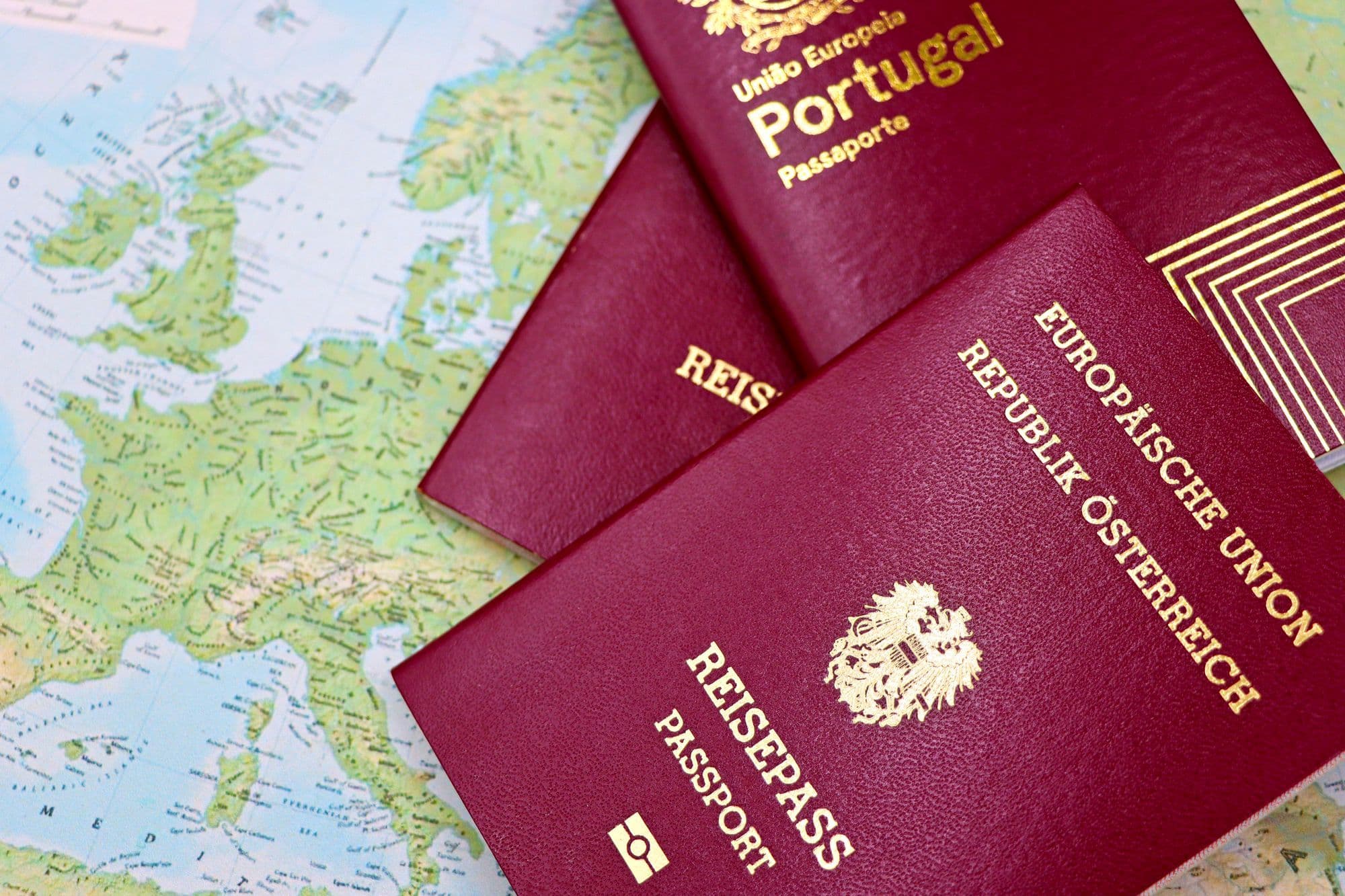 Austrian and Portuguese passports resting on a map of Europe.