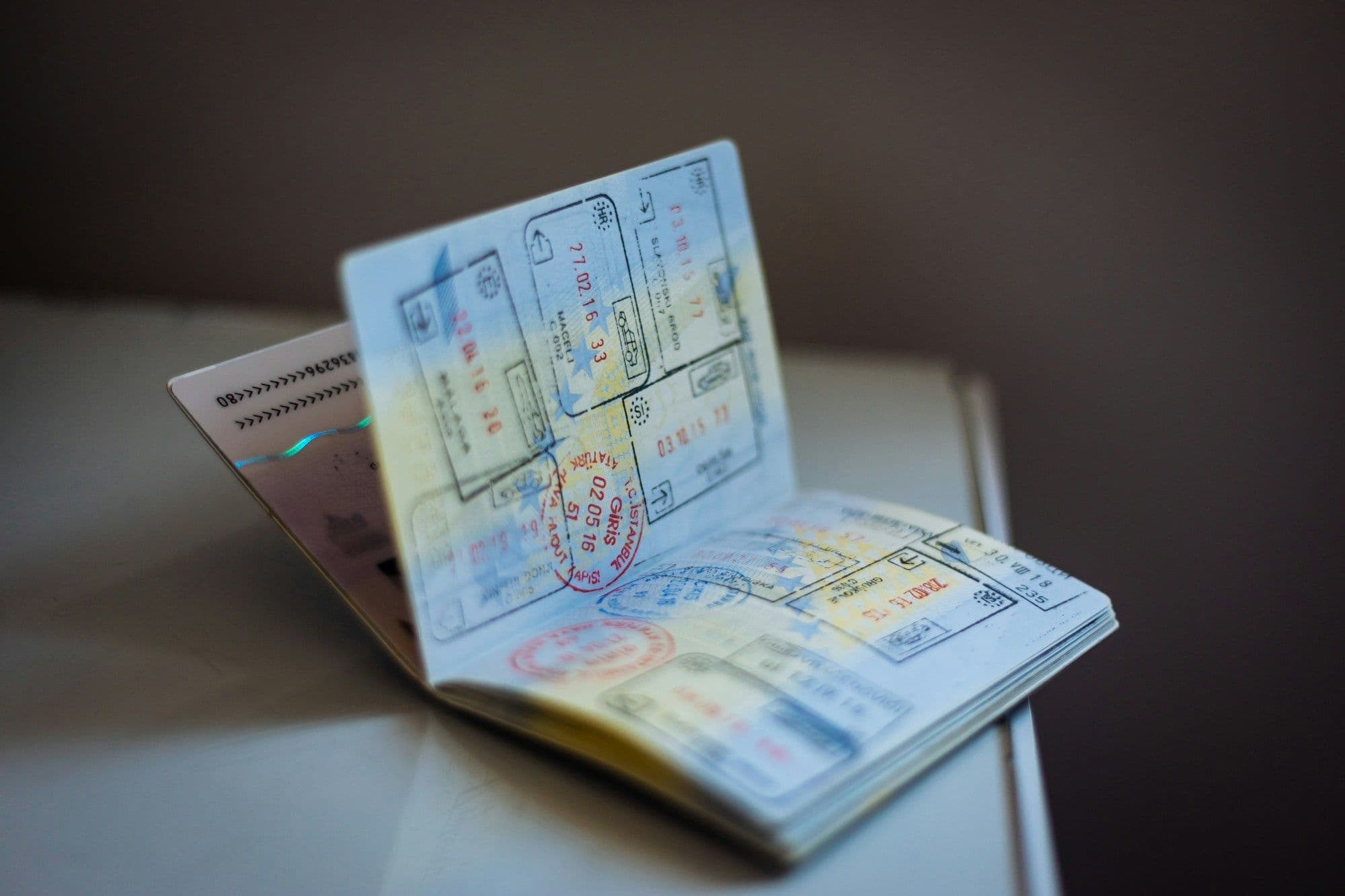 An open passport with pages full of colored entry stamps resting on a table.
