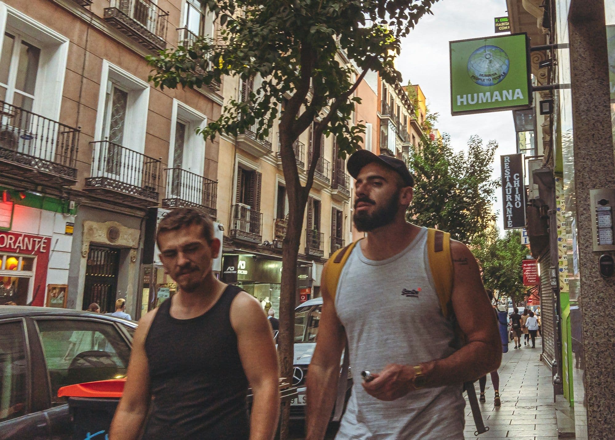 Two men walking side by side along a broad city pavement in daylight.