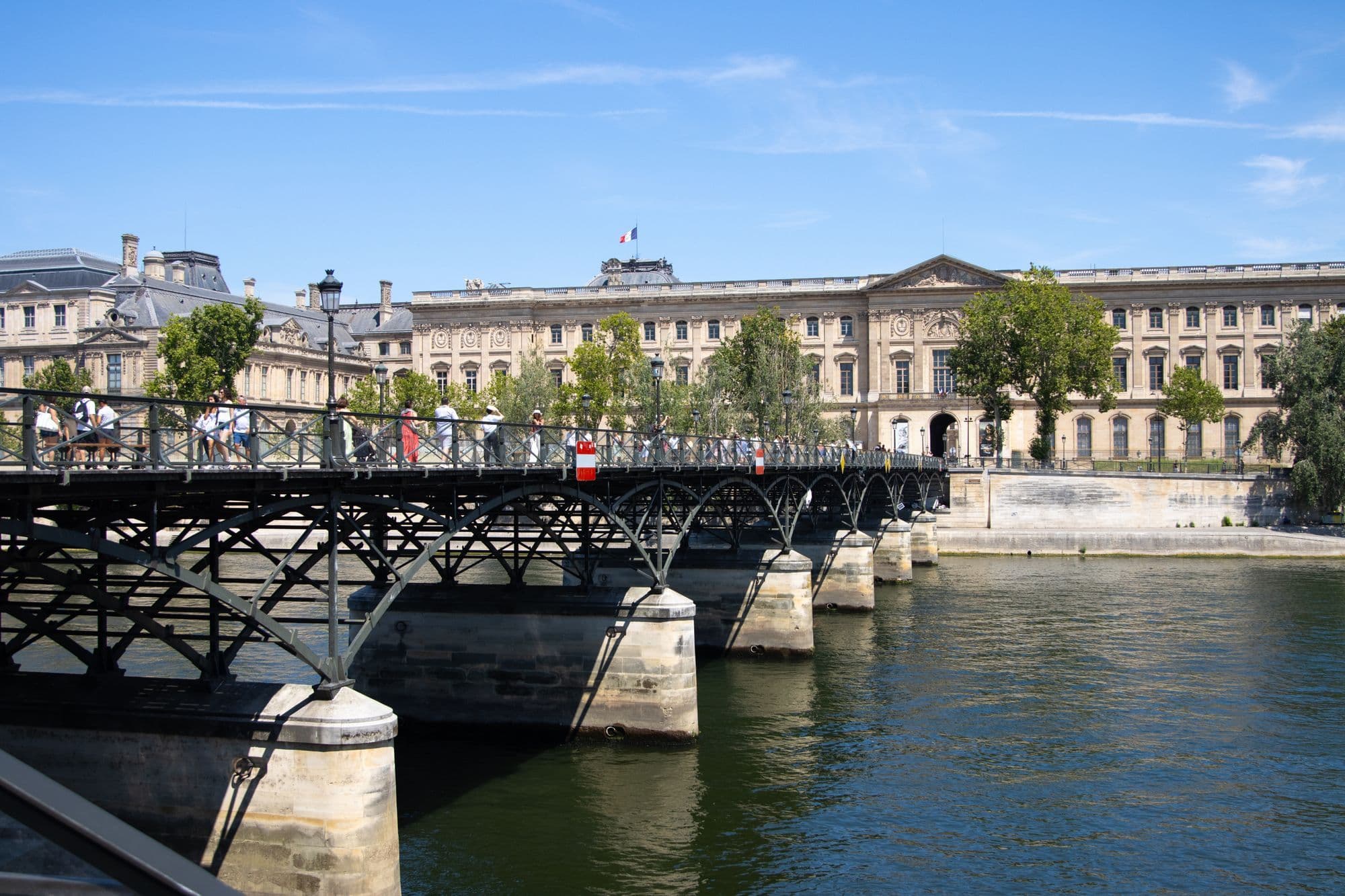 The Pont des Arts crosses the Seine with the Louvre stretching along the opposite bank.