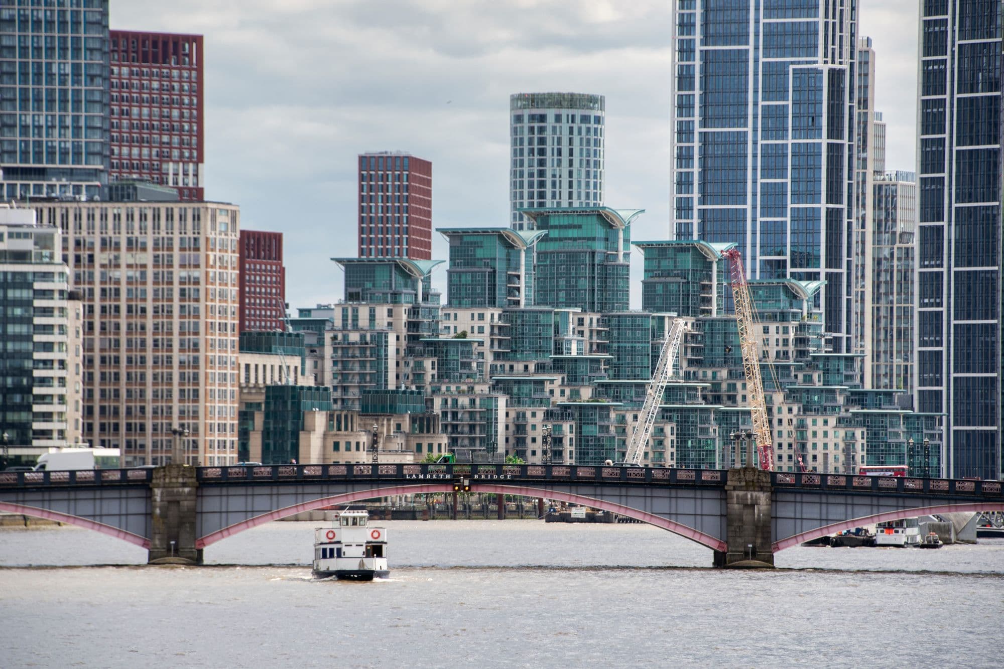 Vauxhall Bridge crossing the Thames beneath modern apartment towers and a cloudy sky.