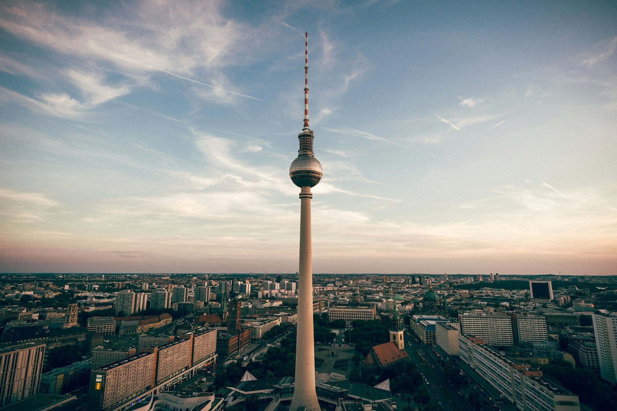 Berlin's television tower rising above rooftops in the warm light before sunset.