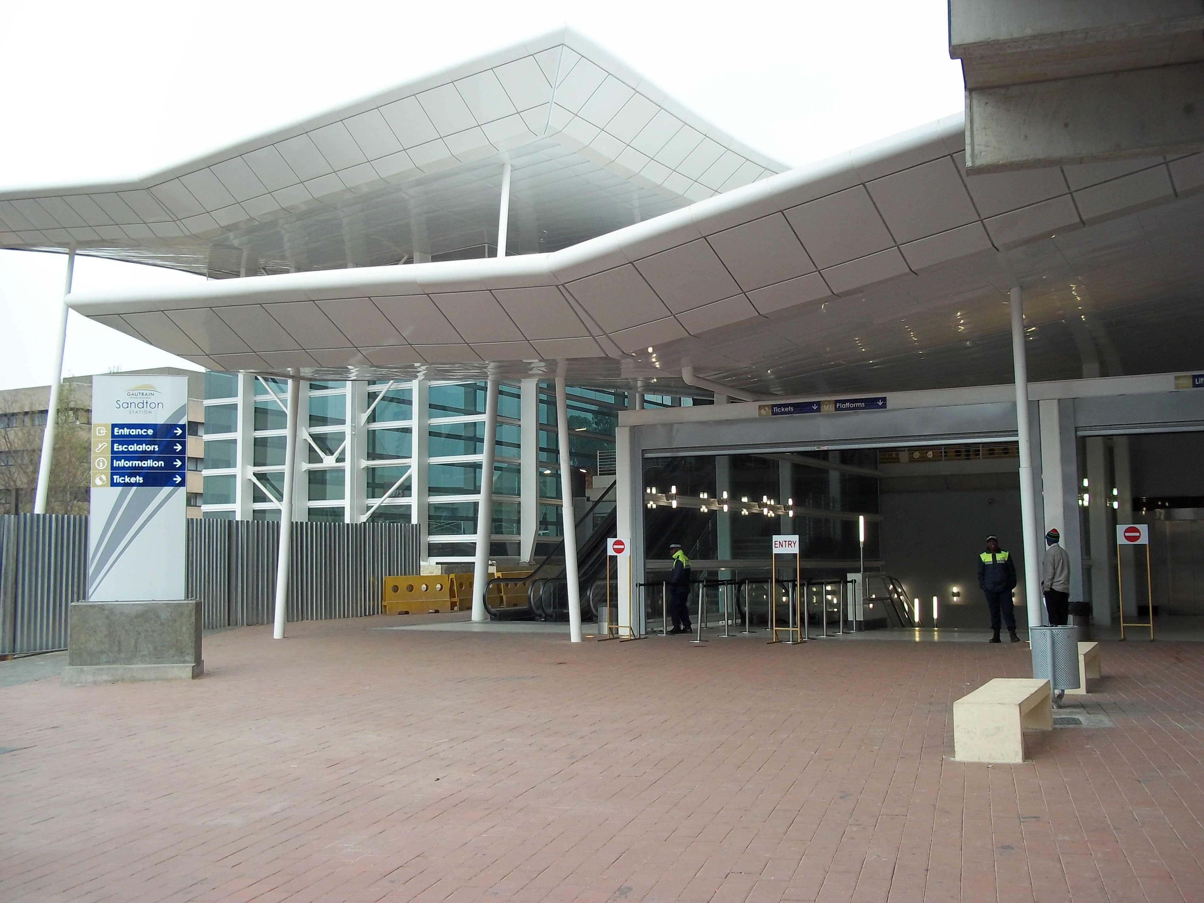 The modern glass-and-steel entrance canopy of Sandton Gautrain station on a sunny day.