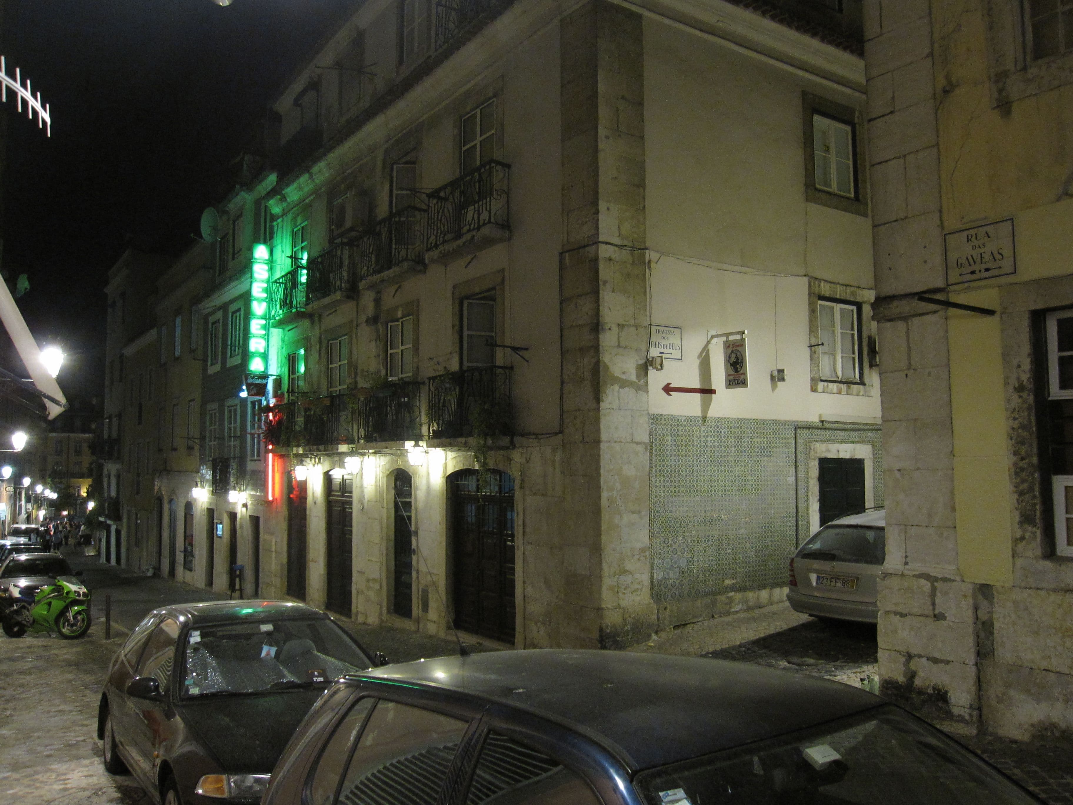 A quiet Bairro Alto corner at night, with a green neon bar sign and the tiled street sign for Rua das Gáveas.