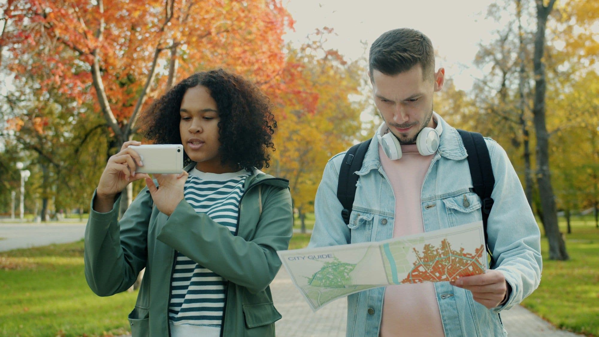 Two travelers looking at a paper map together in a city park.