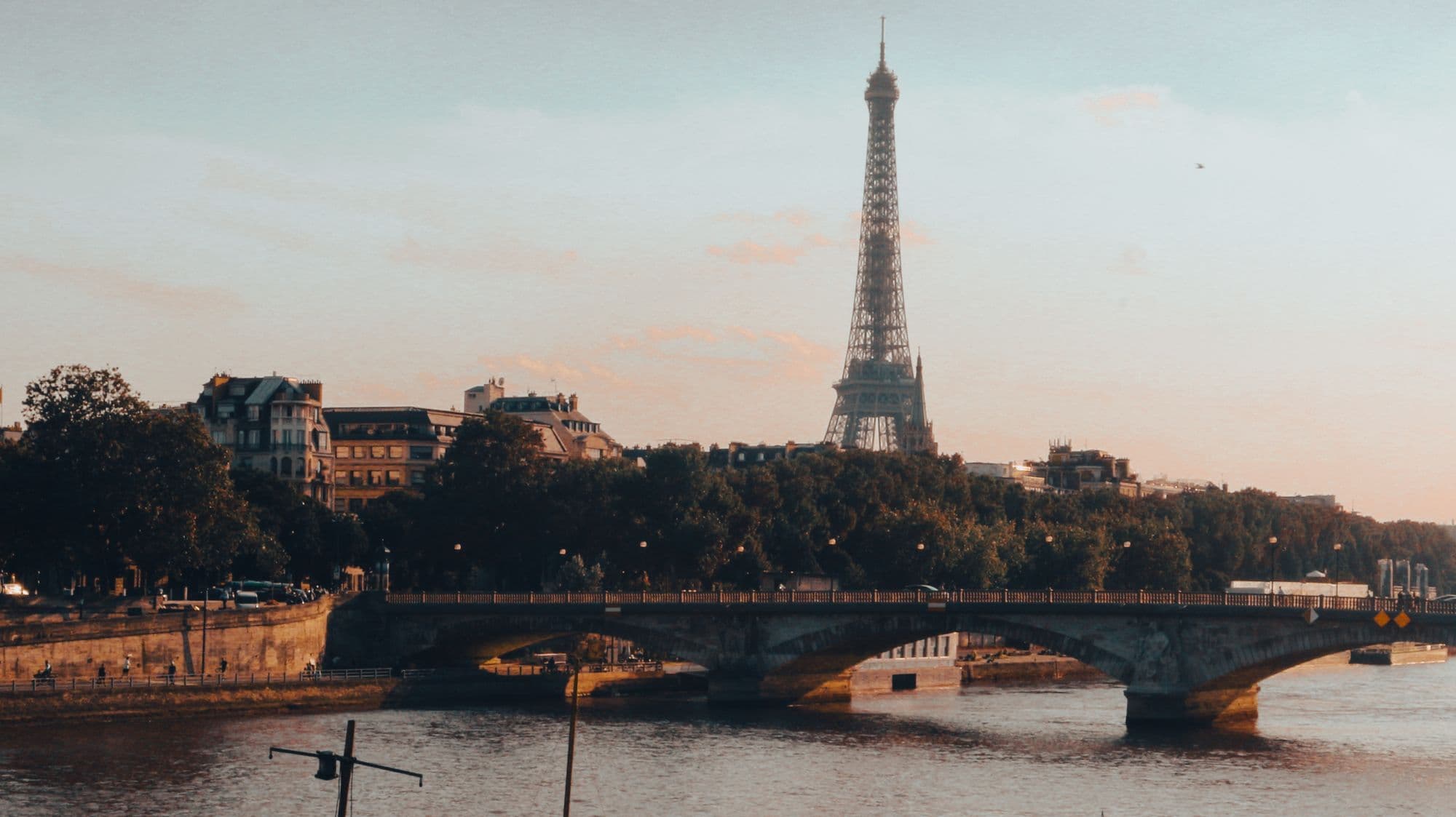 The Eiffel Tower and Seine silhouetted beneath a pink and orange Paris sunset.