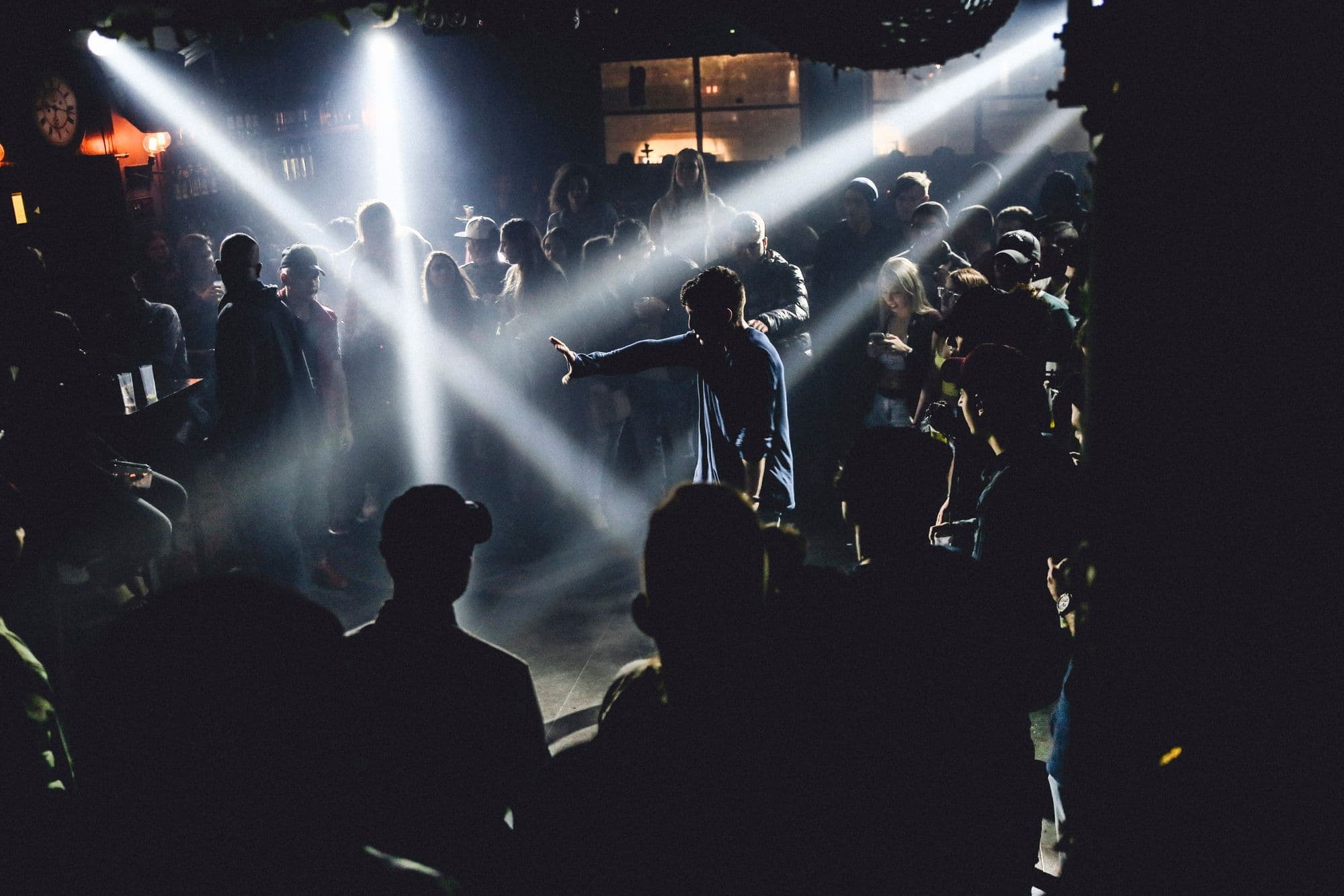 People dance under blue and purple lights in a crowded nightclub.